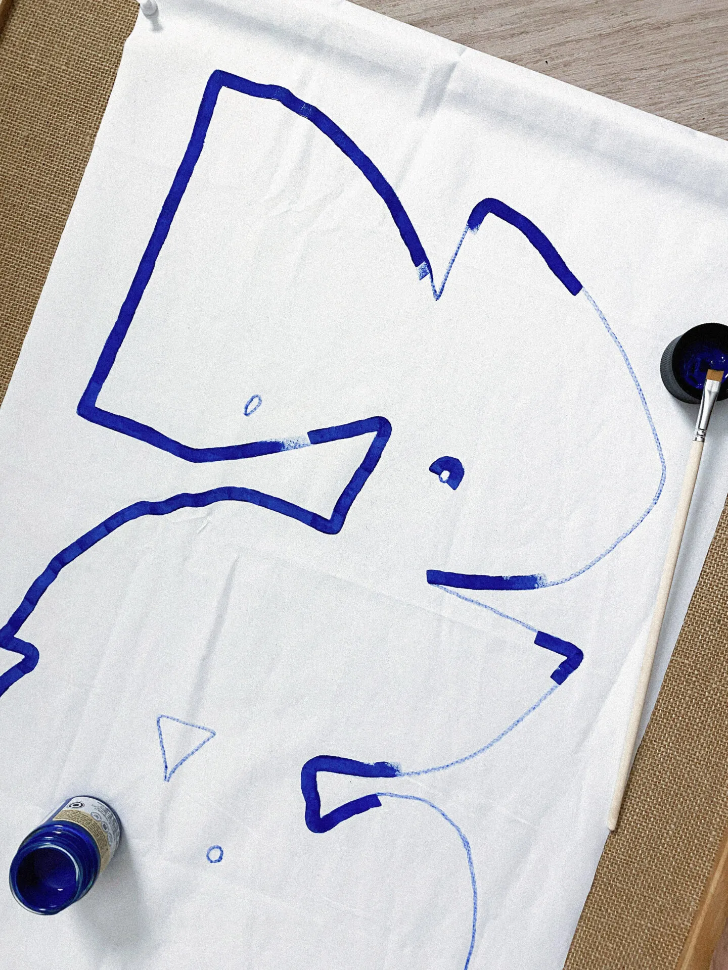 Drapeau de l’EP Mijoteries peint en bleu sur une toile blanche