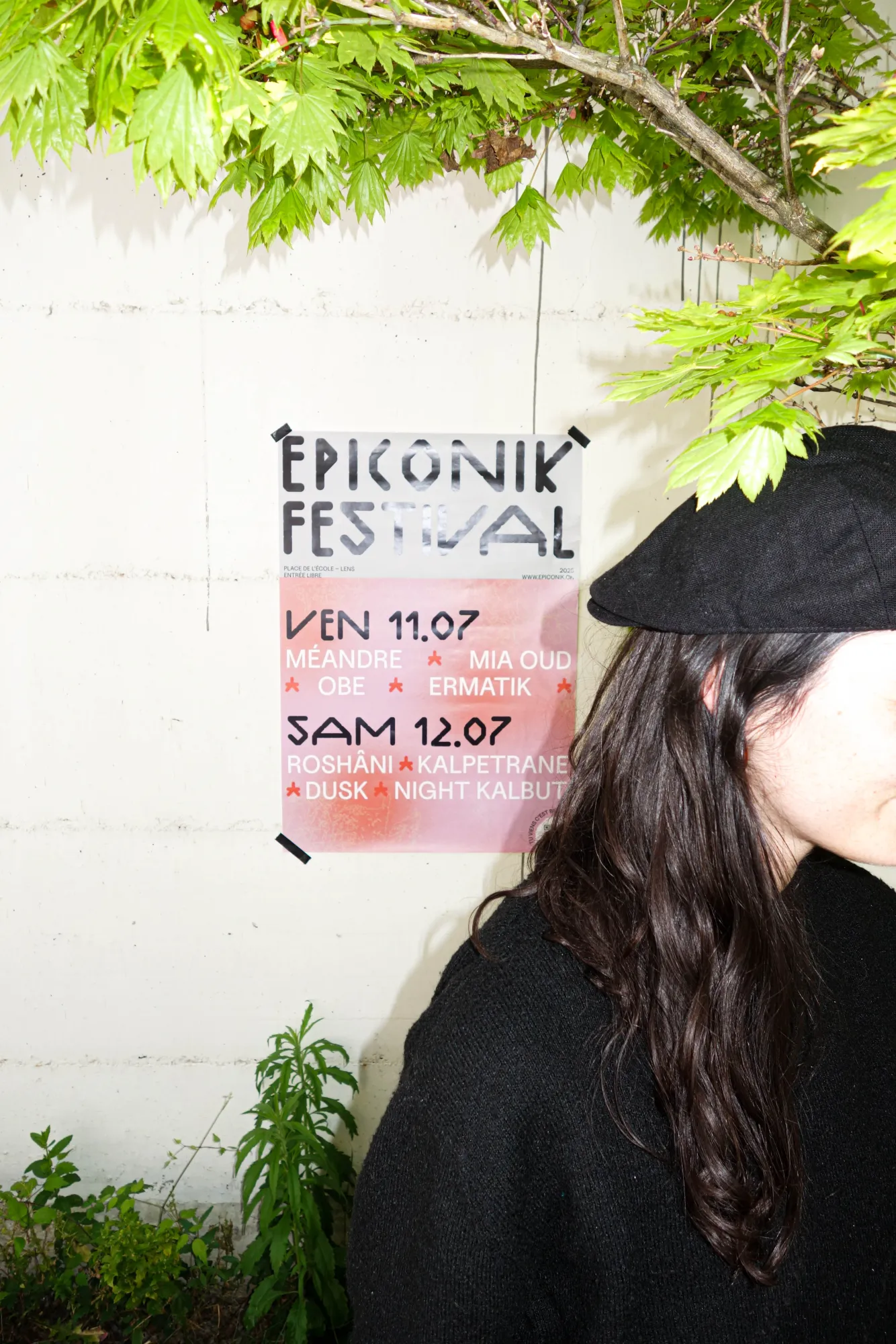 Affiche de l’Epiconik Festival 2025 sur un mur, à côté de Jordane Vincenzi