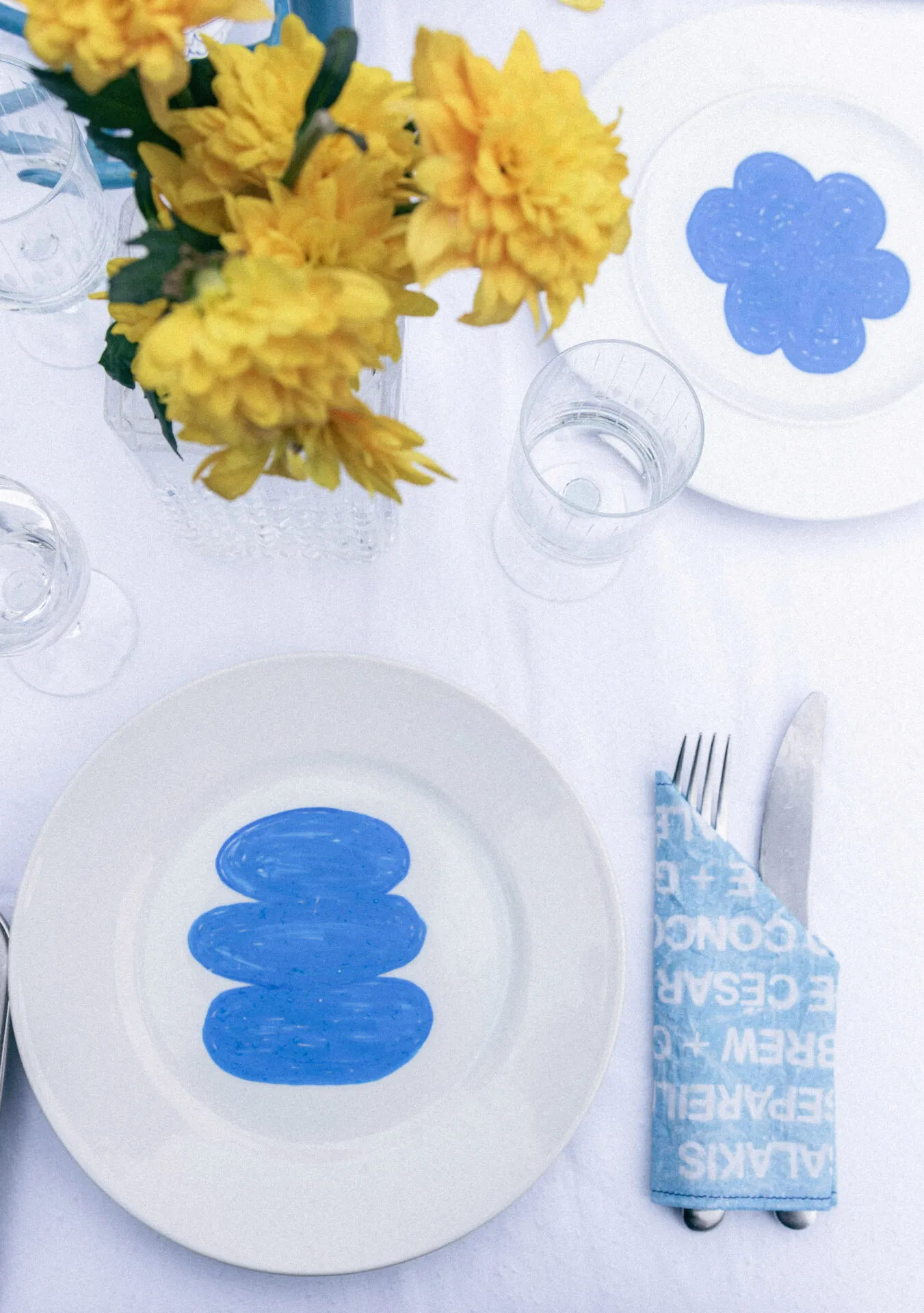 Table dressée de l’EP Mijoteries : assiettes peintes en bleu et fleurs jaunes