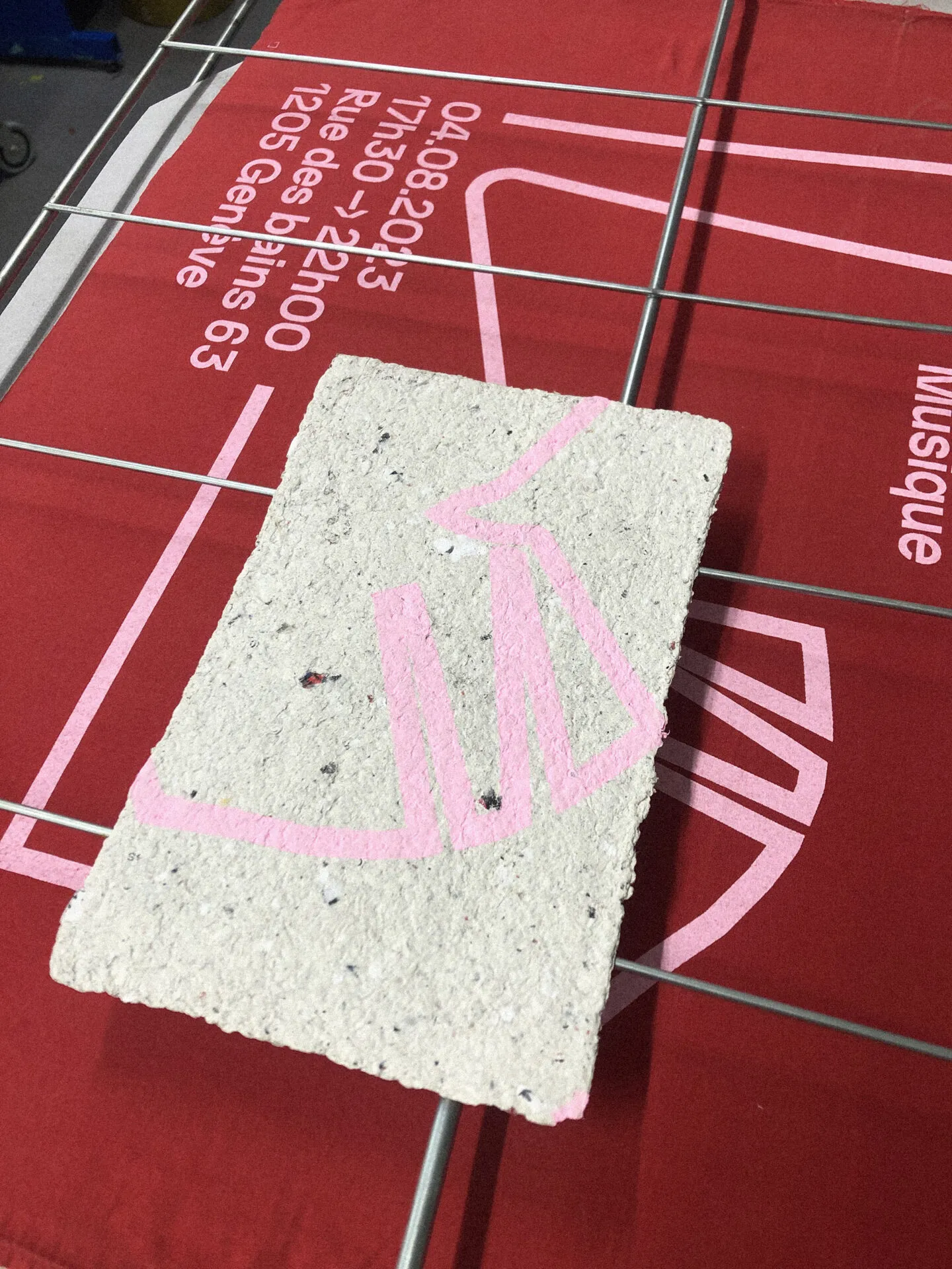 Carte en papier recyclé imprimée en rose en sérigraphie sur une affiche rouge